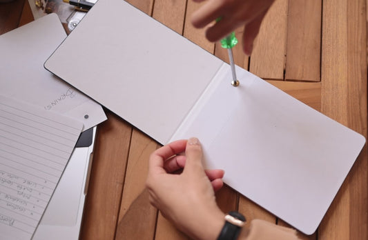 unscrewing the back of my sustainable notepad to refill it with paper once it is empty
